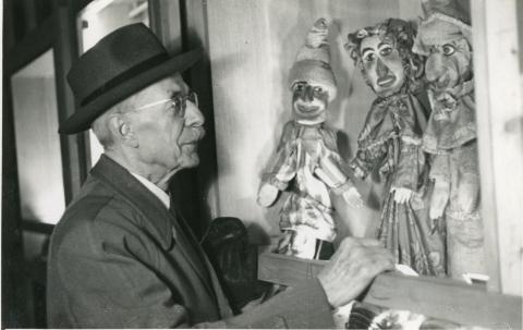 Claude Dalbanne (1877-1964), conservateur de Gadagne de 1937 à 1955, admirant une vitrine présentant Punch et Judy - © Blanc & Demilly, vers 1950